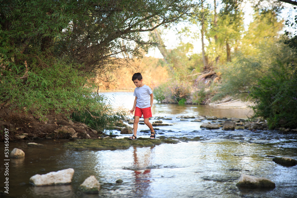 child plays in the river surrounded by nature