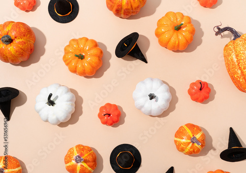 pattern of colorful artificial pumpkins and halloween hats on orange background photo