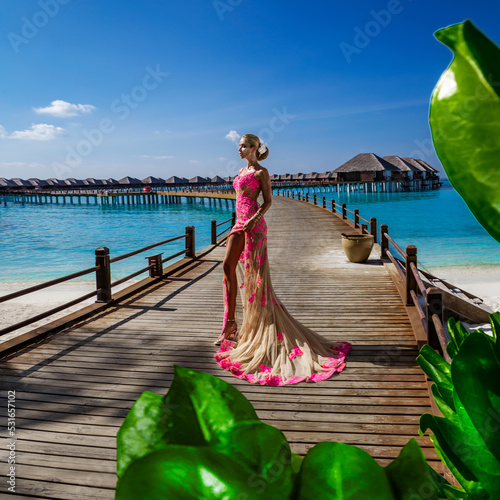 Elegant fashion model in amazing long gown dress is posing on the Maldives sandy beach. Elegance. Couture. Vogue.