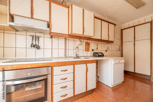 Antique kitchen with edge wood cabinets, chests of drawers and cabinets, light brown flooring and cream tile on the walls