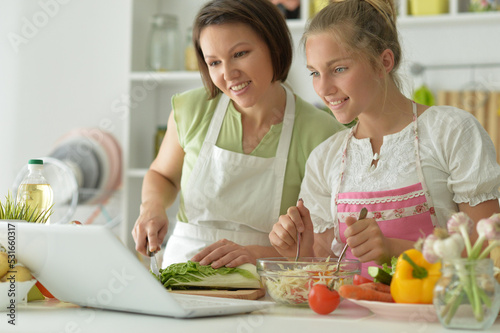 Beautiful girl with her mother preparing a salad in the kitchen