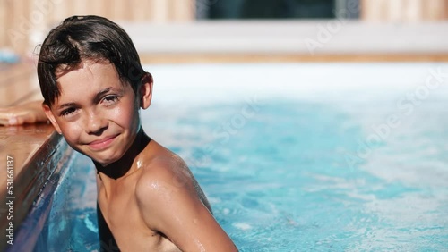 4k video Portrait of smiling handsome boy in swimming pool, child enjoying swimming in summer in pool. Vacation hotel concept.