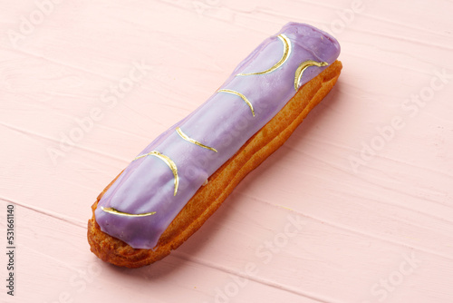 Eclair dessert with icing on pink wooden background