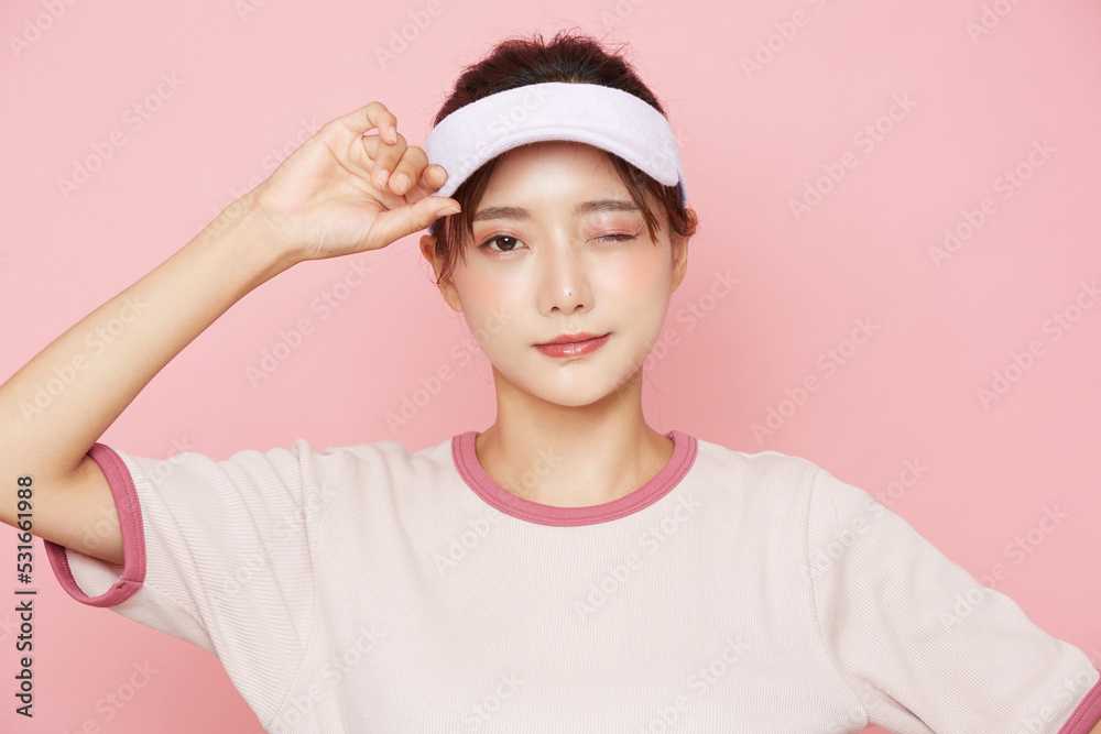 スポーティなファッションをした若い女性のピンク背景のポートレート スポーティなファッションをした若い女性のピンク背景のポートレート
