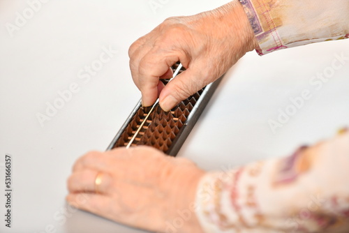 ソロバンをはじく高齢女性の指先 photo