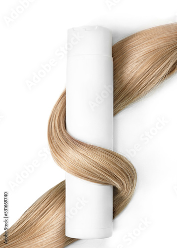 A strand of blond hair with a bottle of shampoo on a white background. Close-up.