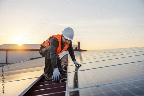 A worker is fixing solar panels on the roof. photo