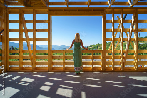Senior woman on site inside construction framing dreaming of her new home and looking at view.