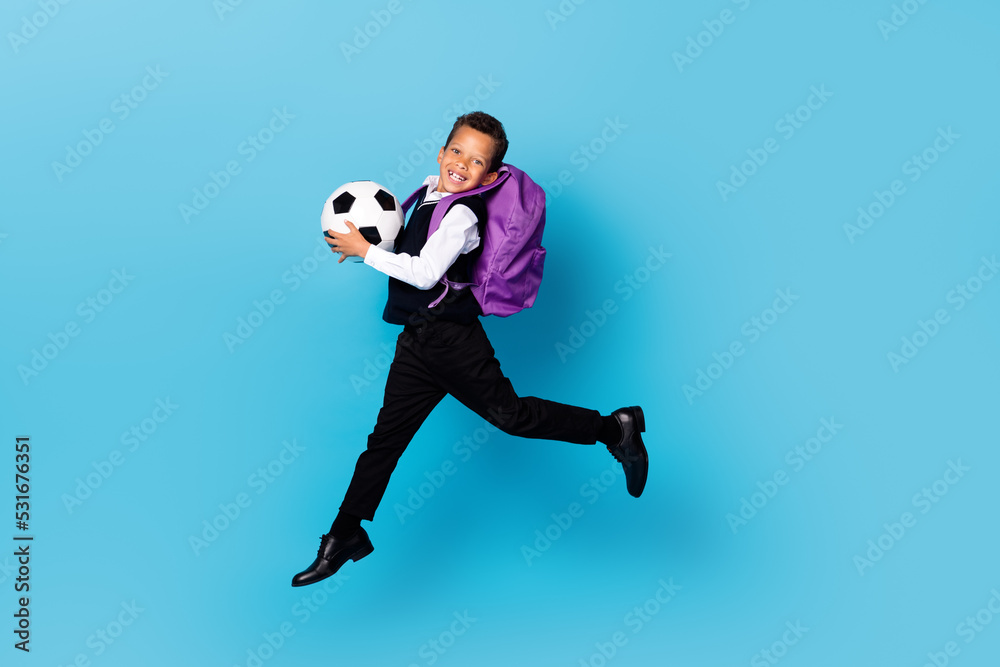 Full size portrait of little person jumping hands hold football isolated on blue color background