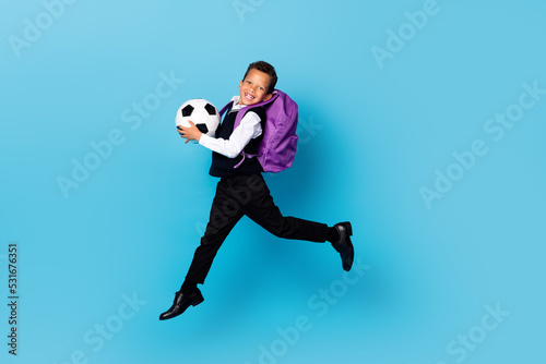 Full size portrait of little person jumping hands hold football isolated on blue color background