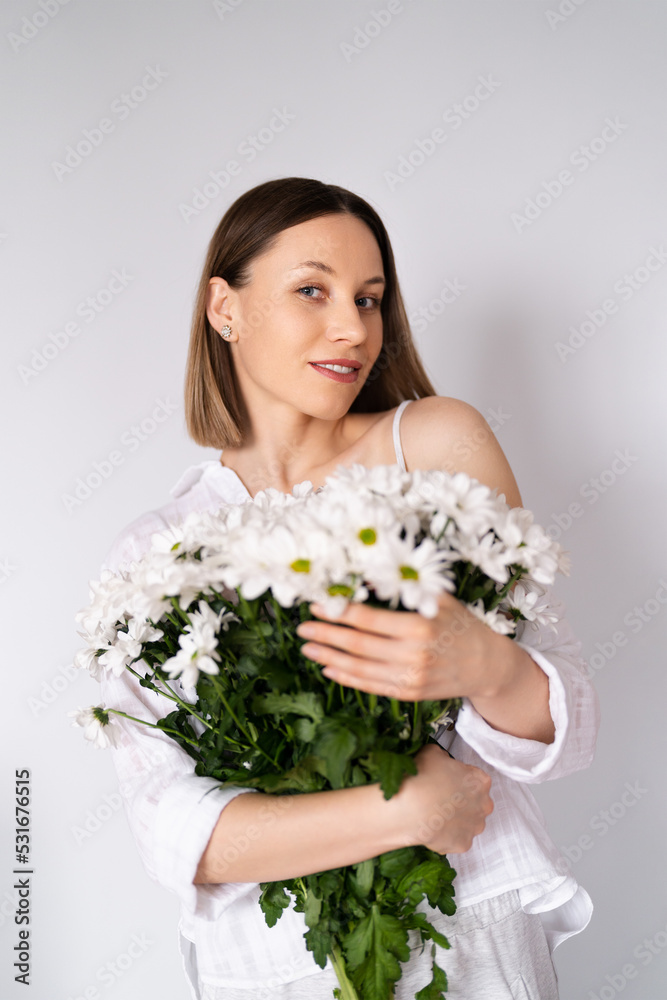 Young beautiful cute sweet lovely smiling woman with hold a bouquet of white fresh flowers on white wall background Young beautiful cute sweet lovely smiling woman with hold a bouquet of white fresh flowers on white wall background