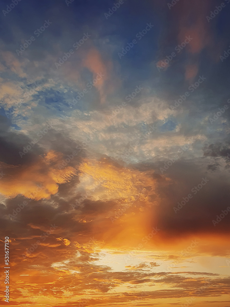 Beautiful sunset sky with colorful orange clouds over the horizon, vertical celestial background