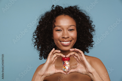 Shirtless black woman smiling while showing pills