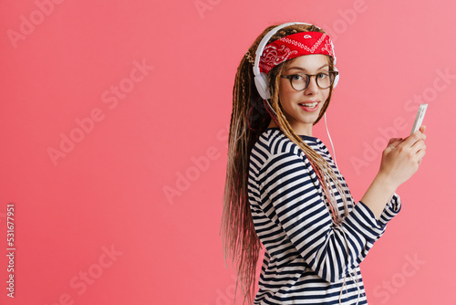 White woman with dreadlocks using cellphone while listening music
