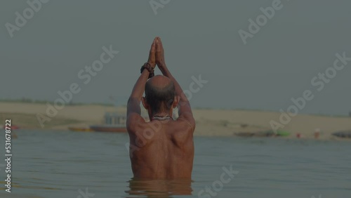 A man doing surya namaskar in ganga river at varanasi ghat photo