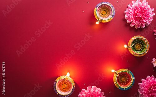 Happy Diwali - Clay Diya lamps lit during Diwali, Hindu festival of lights celebration. Colorful traditional oil lamp diya on red background photo