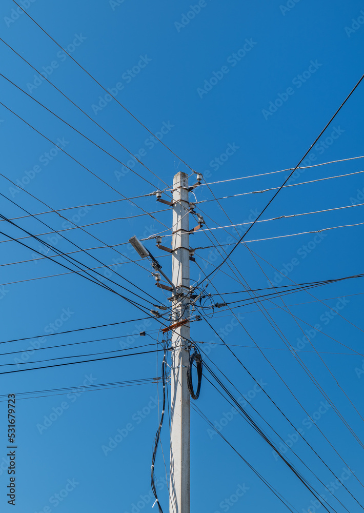 Reinforced concrete power transmission line support. Lots of electrical wires against the blue sky Reinforced concrete power transmission line support. Lots of electrical wires against the blue sky
