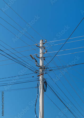 Reinforced concrete power transmission line support. Lots of electrical wires against the blue sky