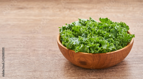 fresh green Kale leaves bunch leaf cabbage in wood plate or bowl on wooden table background. green kale or leaf cabbage                           