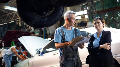 Serious asian young woman customer talking with owner and mechanic worker at car repair service and auto store shop.