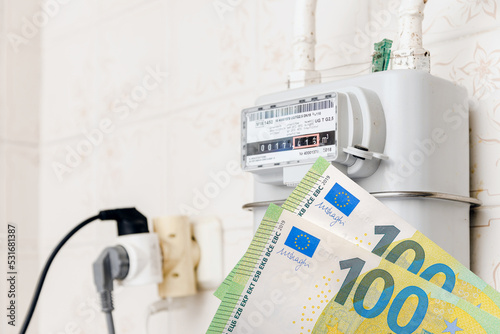 A gas meter in the house.Euro banknotes near.Counter for distribution domestic gas. Symbolic image of a payment for heating and electricity in winter.Selective focus.