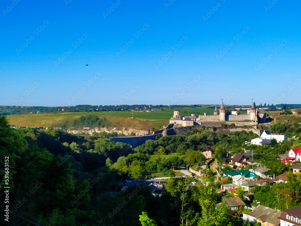 Kamianets Podilsky fortress on summer day. Scenic summer view of ancient fortress castle in Khmelnytskyi Region, Ukraine. Medieval stone large castle fortress with spiers and defensive towers.