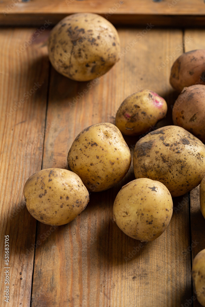 Close up of raw fresh potatoes roots on wooden surface food homegrown Close up of raw fresh potatoes roots on wooden surface food homegrown