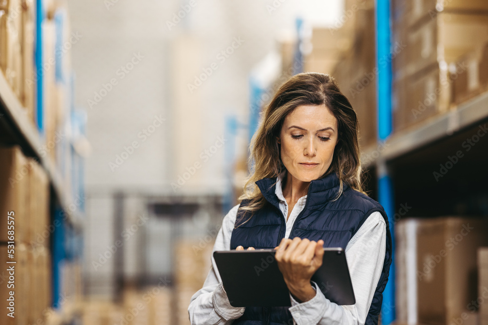 Warehouse worker looking at an inventory list on a digital tablet Warehouse worker looking at an inventory list on a digital tablet