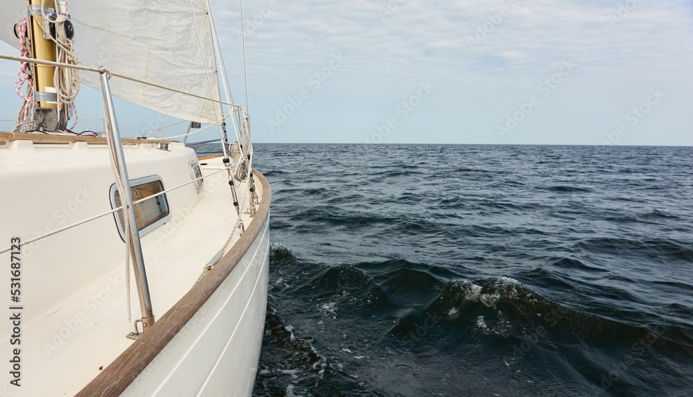 White sloop rigged yacht sailing in the Baltic sea after the storm. Waves, splashes, water surface. Cruise, summer vacations, regatta, sport, leisure activity, tourism, wanderlust concepts White sloop rigged yacht sailing in the Baltic sea after the storm. Waves, splashes, water surface. Cruise, summer vacations, regatta, sport, leisure activity, tourism, wanderlust concepts