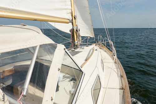 White sloop rigged yacht sailing in the Baltic sea after the storm. Waves  splashes  water surface. Cruise  summer vacations  regatta  sport  leisure activity  tourism  wanderlust concepts