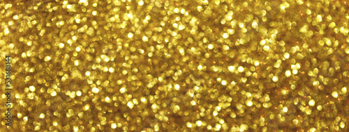 Blurred golden sparkling background from small sequins, macro. Shiny yellow glittery bokeh of christmas garland.