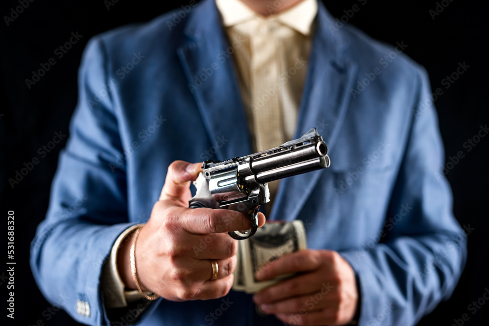 Sniper man in black suit gesturing and boldly holding gun on isolated black background. Sniper man in black suit gesturing and boldly holding gun on isolated black background.