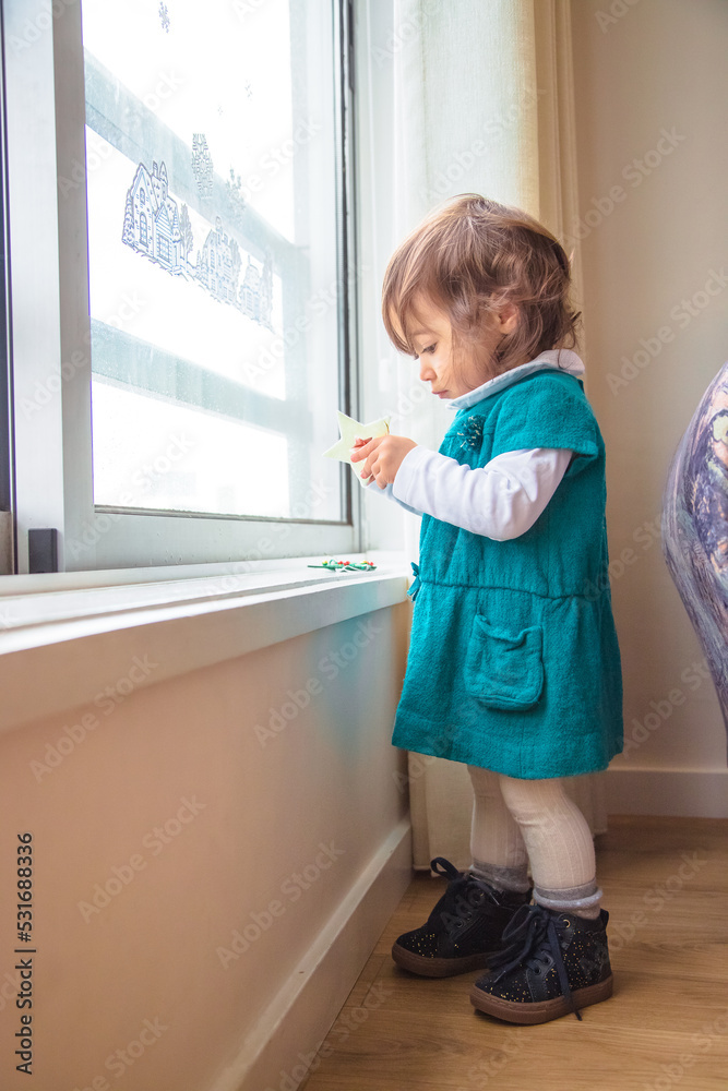 Little Girl Standing In Front Of The Window Of Her House Having Fun little-girl-standing-in-front-of-the-window-of-her-house-having-fun