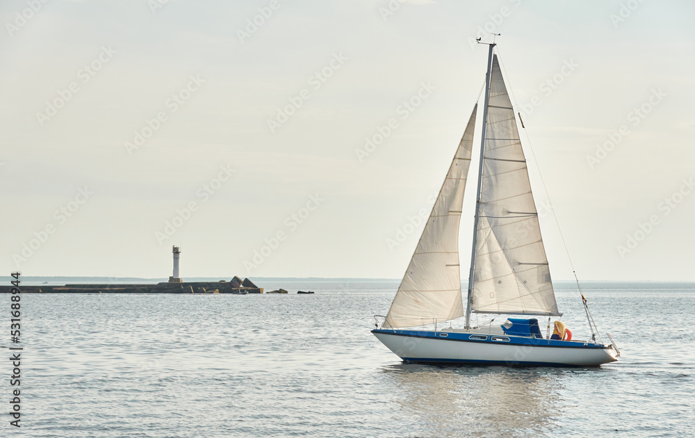 White sloop rigged yacht sailing in the Baltic sea on a clear day. Transportation, cruise, yachting, regatta, sport, recreation themes. Travel, exploring, wanderlust concepts