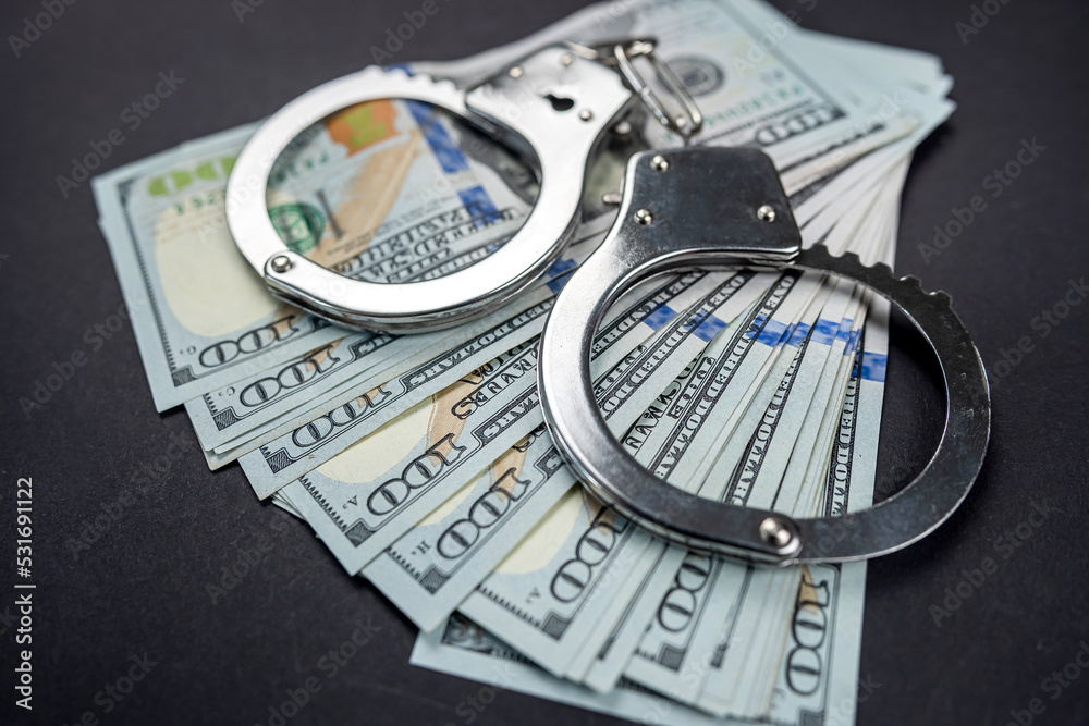 Banknotes dollars money and handcuffs isolated on black background. Banknotes dollars money and handcuffs isolated on black background.
