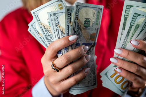 top view of female boss hands holding many cash dollars isolated on plain background.