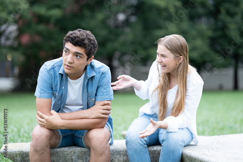 Bored teenager boy listening excited girl talking too much outdoors in a park © Egoitz