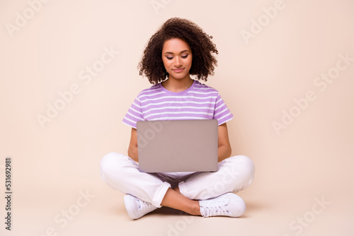 Full body size photo of young attractive girl sitting using laptop comfort worker distant freelancer isolated on beige color background