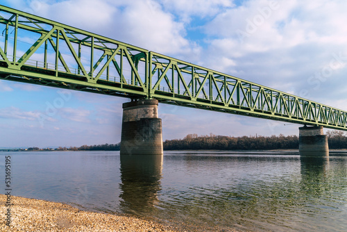 a green railroad bridge over a river