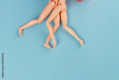 Pair of naked doll bodies on blue background. Legs of hugging couple.