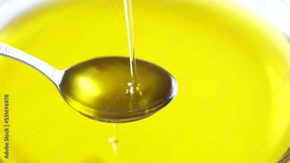 Pouring extra virgin olive oil on spoon Pouring extra virgin olive oil on spoon