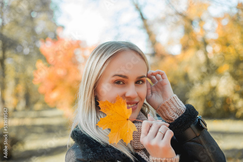 Beautiful young blonde woman in autumn park. Portrait of a happy model in casual clothes. Cosy. Fall.
