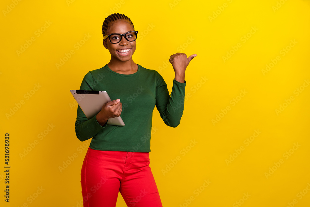 Photo of adorable shiny lady dressed green shirt eyewear holding modern gadget thumb empty space isolated yellow color background Photo of adorable shiny lady dressed green shirt eyewear holding modern gadget thumb empty space isolated yellow color background