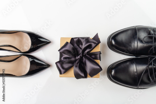 Top view of mens and womens shoes and a gift box with black ribbon. Fashionable and stylish accessories. Sale and delivery of shoes concept.