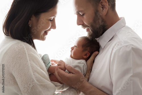 Family with Newborn Baby. Happy Parents holding one month Child. Smiling Mother and Father Silhouette with Infant over White. Parenting Love and Childcare