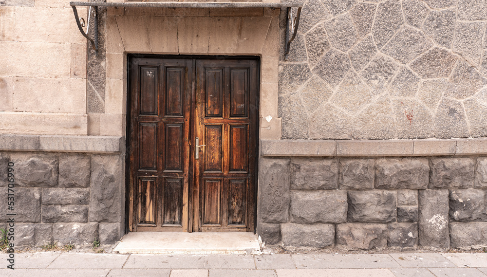 Old classical stone house with rustic, brown, carved, vintage wooden door. Door textures and backgound.