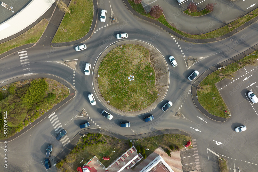 Aerial view of road roundabout intersection with fast moving heavy traffic. Urban circular transportation crossroads Aerial view of road roundabout intersection with fast moving heavy traffic. Urban circular transportation crossroads