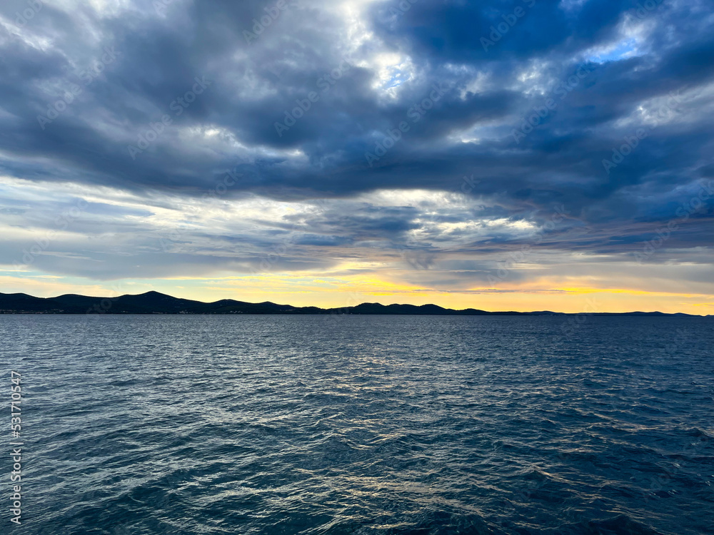 Obraz premium Evening sea view, cloudy sky and yellow sun light, sea horizon 