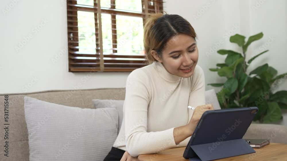 Young pretty Asian woman using tablet in living room. Young pretty Asian woman using tablet in living room.