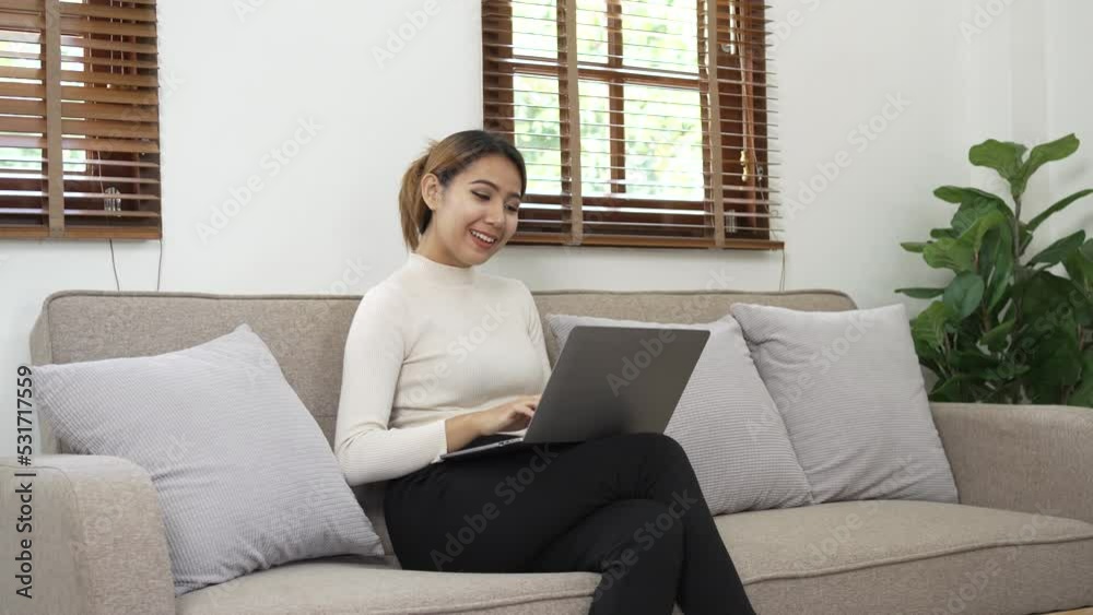 Pretty asian woman using laptop, sitting on sofa. Pretty asian woman using laptop, sitting on sofa.